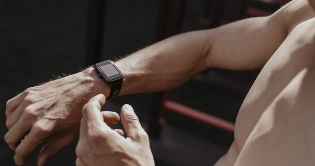 Shirtless athlete using smartwatch while resting workout. Fitness gadgets concept. Space for text. Copy space
